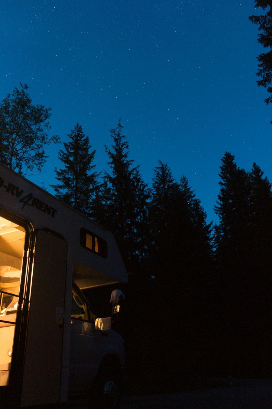 A camper van lit from inside under a night sky